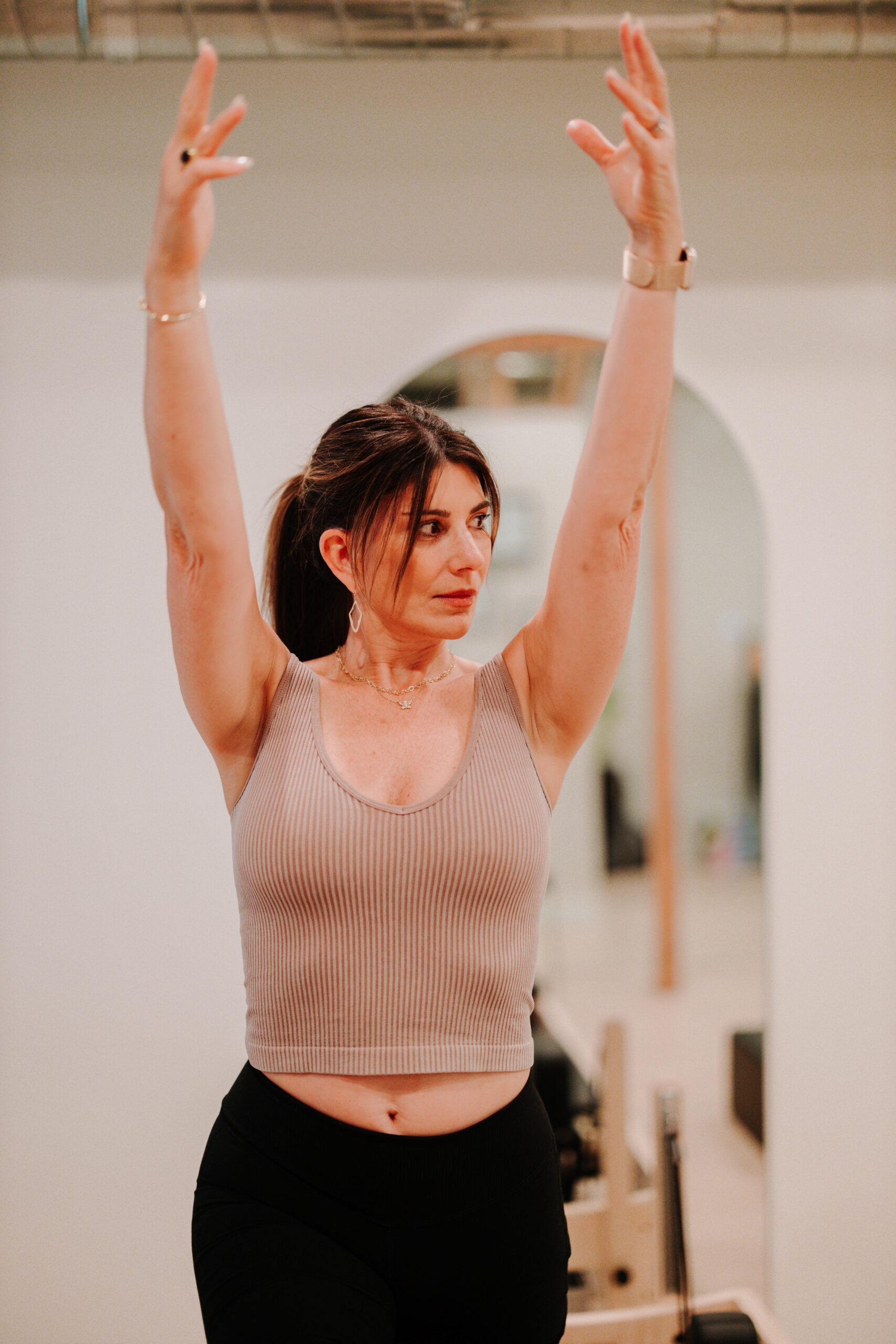 A YA FIT member reaching overhead with strength and control