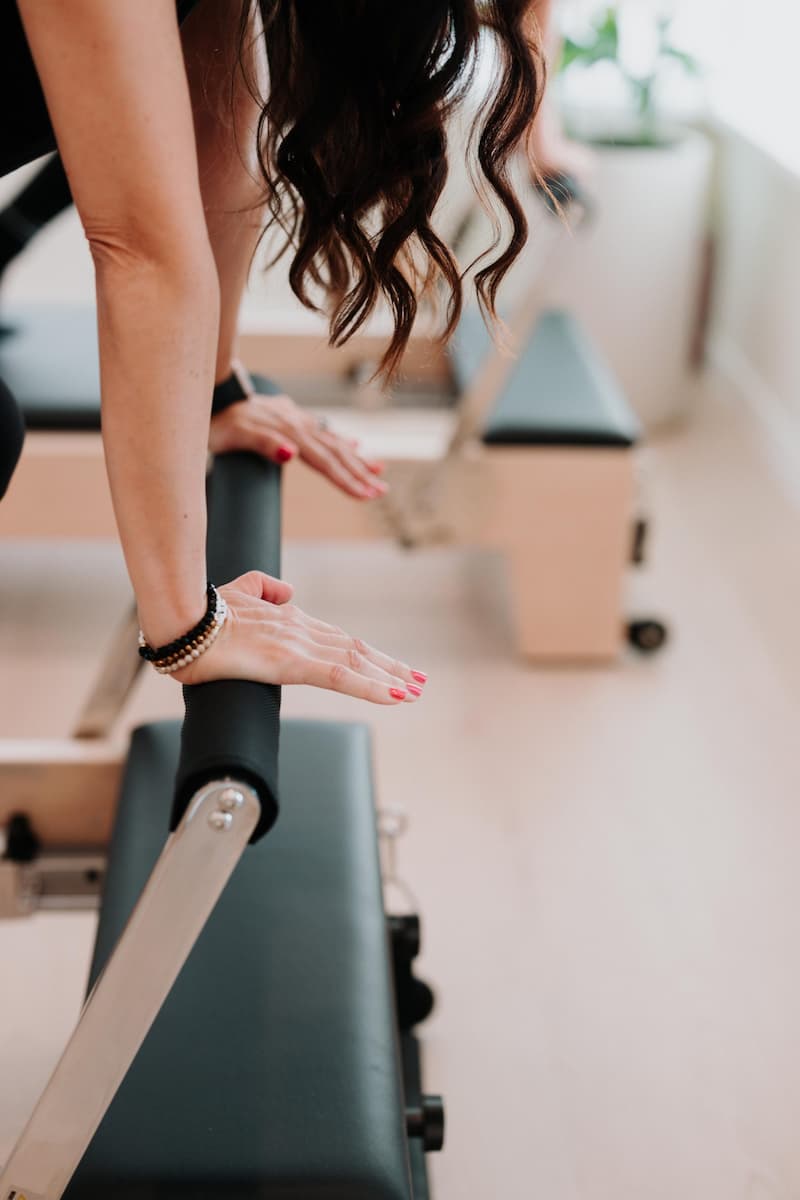 Hand on reformer foot bar at YA FIT Pilates